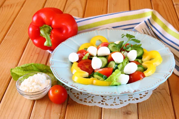 Salat mit Mozzarella und frischem Gemüse auf Holztischhintergrund. — Stockfoto