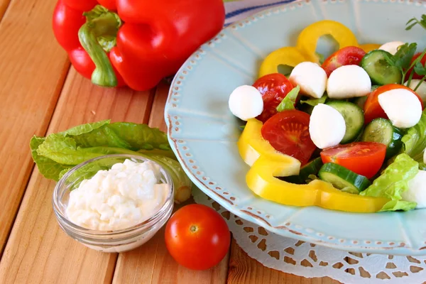 Salade met mozzarella en verse groenten op houten tafel achtergrond. — Stockfoto