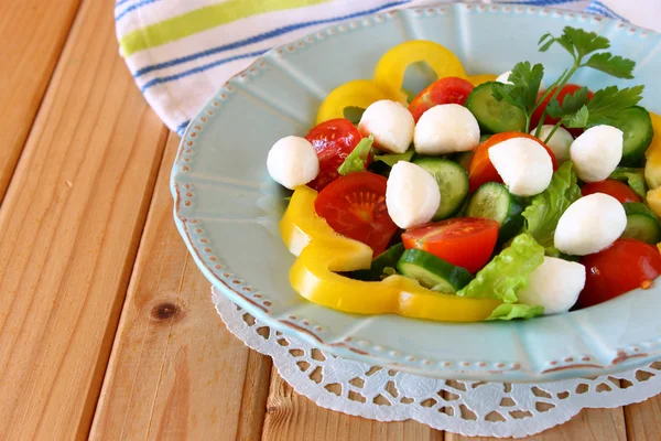Salat mit Mozzarella und frischem Gemüse auf Holztischhintergrund. — Stockfoto