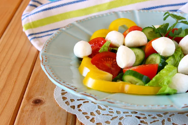 Salade met mozzarella en verse groenten op houten tafel achtergrond. — Stockfoto