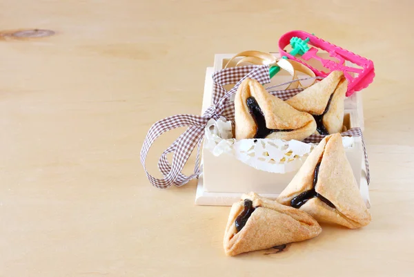 Hamantaschen печенье или hamans уши для празднования Пурим в деревянной коробке и Noisemaker — стоковое фото