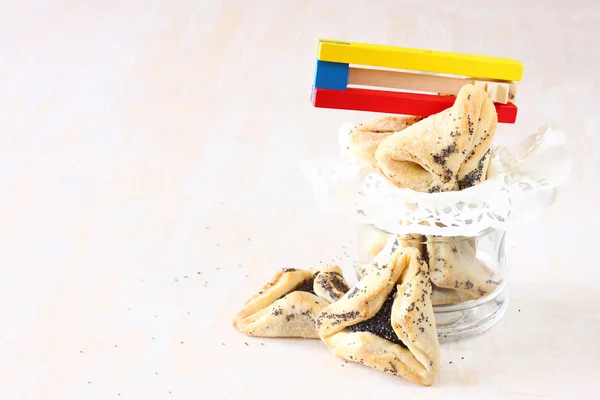 Hamantaschen cookies or hamans ears for Purim celebration and noisemaker over textured wooden board — Stock Photo, Image