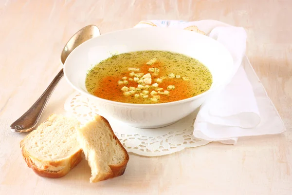 Kyllingsuppe med gulrøtter over hvit, teksturert bakgrunn av tre – stockfoto