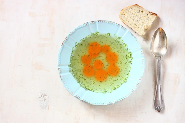 Kyllingsuppe med gulrøtter over hvit, teksturert bakgrunn av tre – stockfoto