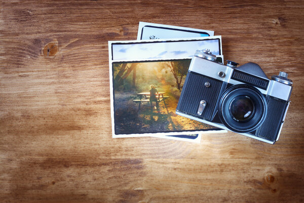 Вид сверху старой винтажной камеры и фотографии на деревянном коричневом фоне
.