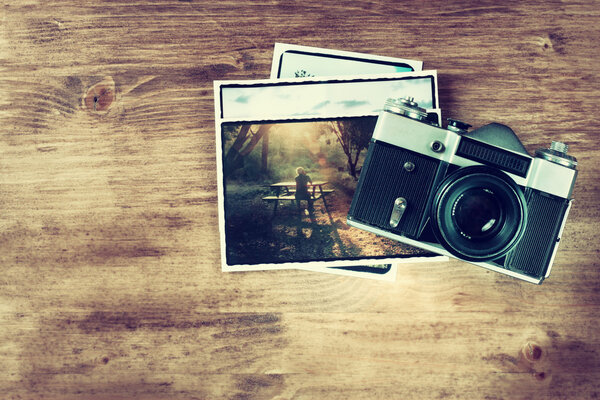 Top view of old vintage camera and pictures over wooden brown background.