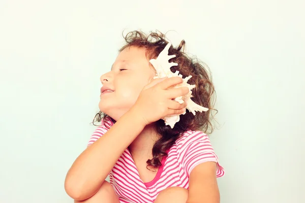 Un ragazzo curioso ascolta la conchiglia. concetto di scoperta e apprendimento . — Foto Stock