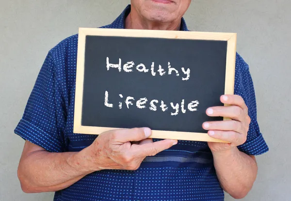 Close-up de homem sênior segurando quadro negro com a frase seguro de saúde escrito nele . — Fotografia de Stock