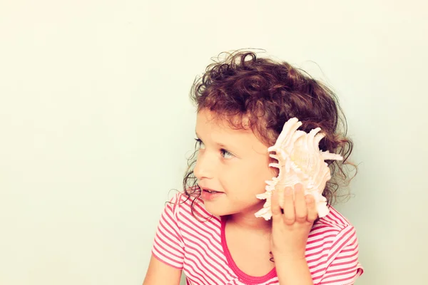 Niño curioso escuchar concha marina . — Foto de Stock