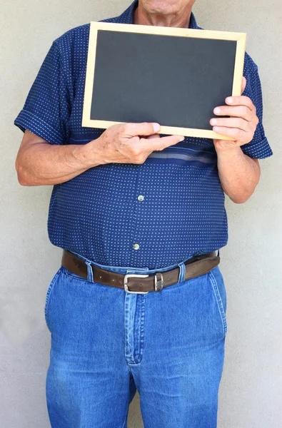 Senior man met witte lege tekenpapier voor zijn gezicht. — Stockfoto