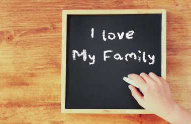 Çocuk el tebeşir ailemi seviyorum yazma yazı tahtası üzerinde tutarak.