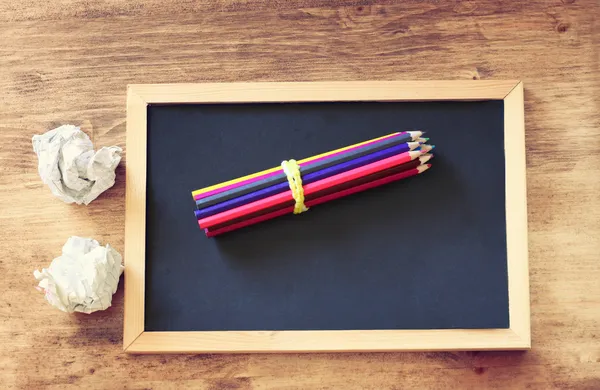 Top view of pencils stack over blackboard and crumpled paper. room for text — Stock Photo, Image