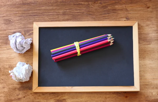 Top view of blackboard , stack of pencils and crumpled paper. — Stock Photo, Image