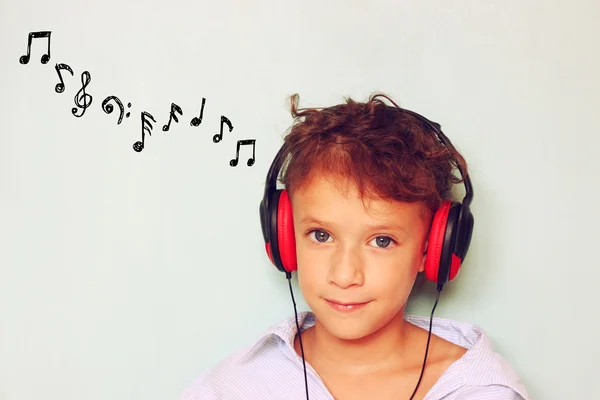 Miúdo bonito (menina) com fones de ouvido se divertindo ouvindo música, e notas esboços . — Fotografia de Stock