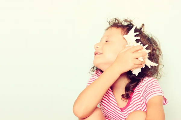Criança curiosa ouvir a concha — Fotografia de Stock