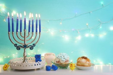 Menorah (geleneksel şamdan), donut ve mumlarla Yahudi bayramı Hanuka arkaplanının dini görüntüsü