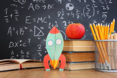 Okul kitapları formüllü karatahtanın önünde. eğitim kavramı