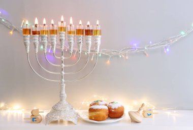 Menorah (geleneksel şamdanlı), donutlar, dönen top ve yağ mumlarıyla Yahudi bayramı arkaplanının dini görüntüsü