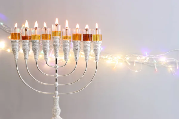 ユダヤ教の休日のイメージメノラ 伝統的なキャンドルラブラ とガーランドグリッターライトを背景にオイルキャンドル — ストック写真