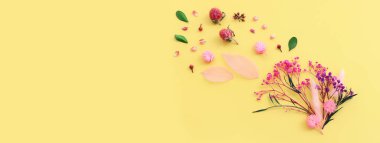 Sarı arkaplan üzerinde pembe, mor ve yeşil çiçek kompozisyonu üst görünüm .Düz yatıyordu