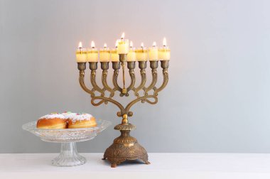 Menora (geleneksel şamdan), donut ve yağ mumlarıyla Yahudi bayramı Hanuka arkaplanının dini görüntüsü