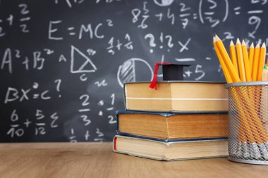 Tahtanın önünde formüllü kalemler ve mezuniyet şapkası. eğitim kavramı