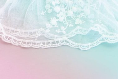 Beyaz, narin dantel kumaşın arka planı, pastel tonlu.