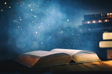 Tahta masanın üzerinde parıltılı kaplamalı açık antik kitap görüntüsü