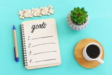 Üst görünüm iş konsepti 2022 gol listesi, defter, ahşap masa üzerinde bir fincan kahve.