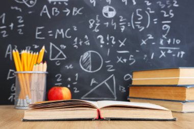 Okul kitapları formüllü karatahtanın önünde. eğitim kavramı