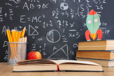 Okul kitapları formüllü karatahtanın önünde. eğitim kavramı