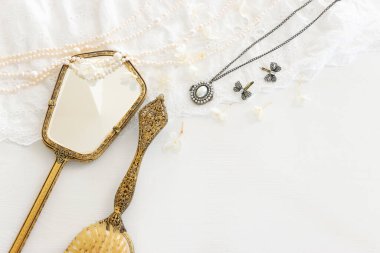 Beyaz, narin dantel kumaş, inciler ve klasik el aynasının arka planı.