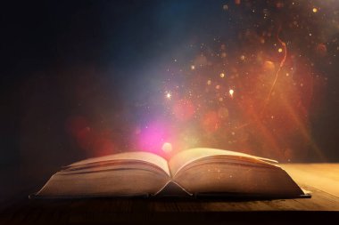 Tahta masanın üzerinde parıltılı kaplamalı açık antik kitap görüntüsü