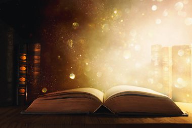 Tahta masanın üzerinde parıltılı kaplamalı açık antik kitap görüntüsü