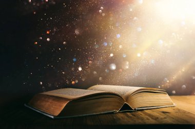 Tahta masanın üzerinde parıltılı kaplamalı açık antik kitap görüntüsü