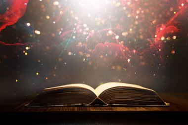 Tahta masanın üzerinde parıltılı kaplamalı açık antik kitap görüntüsü