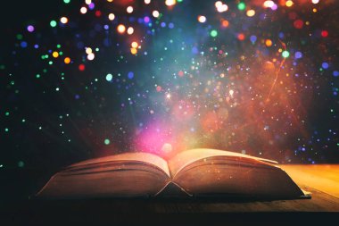 Tahta masanın üzerinde parıltılı kaplamalı açık antik kitap görüntüsü