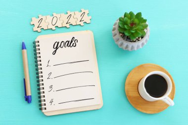 Üst görünüm iş konsepti 2022 gol listesi, defter, ahşap masa üzerinde bir fincan kahve.