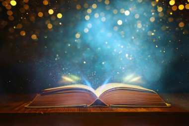Tahta masanın üzerinde parıltılı kaplamalı açık antik kitap görüntüsü
