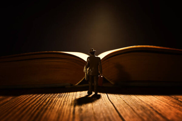 Miniature man stands in front of open book. Concept of dream and fantasy