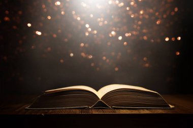 Tahta masanın üzerinde parıltılı kaplamalı açık antik kitap görüntüsü