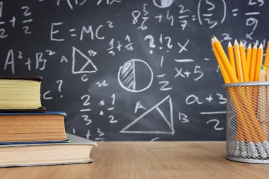 Tahtanın önünde formüllü kalemler ve kitaplar. eğitim kavramı