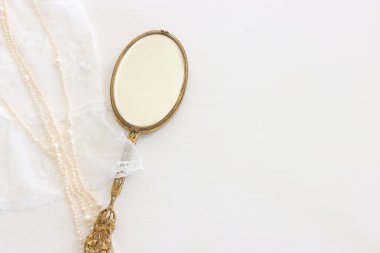 Beyaz, narin dantel kumaş, inciler ve klasik el aynasının arka planı.
