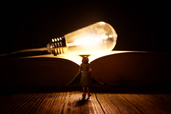 Image of woman looking at glowing light bulb. Concept of finding the right idea, or solution