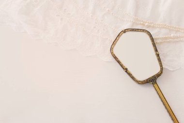 Beyaz, narin dantel kumaş, inciler ve klasik el aynasının arka planı.