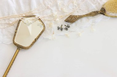 Beyaz, narin dantel kumaş, inciler ve klasik el aynasının arka planı.