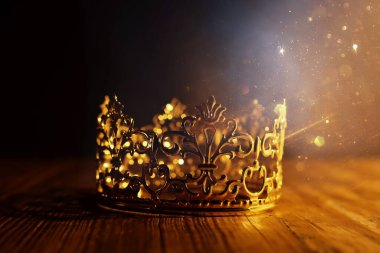 Tahta masanın üzerindeki güzel kraliçe ve kral tacının gösterişsiz görüntüsü. Eski model filtrelenmiş. fantezi ortaçağ dönemi