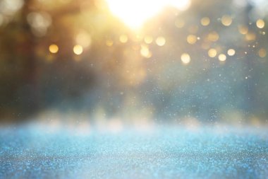 Ağaçlar arasında ışık patlaması ve parlak altın bokeh ışıklarının bulanık fotoğrafı.