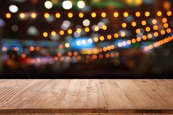 在抽象模糊的餐厅灯光前的木制桌子图像 — 图库照片