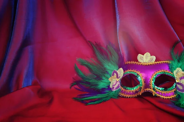 Photo of elegant and delicate Venetian mask over red silk background